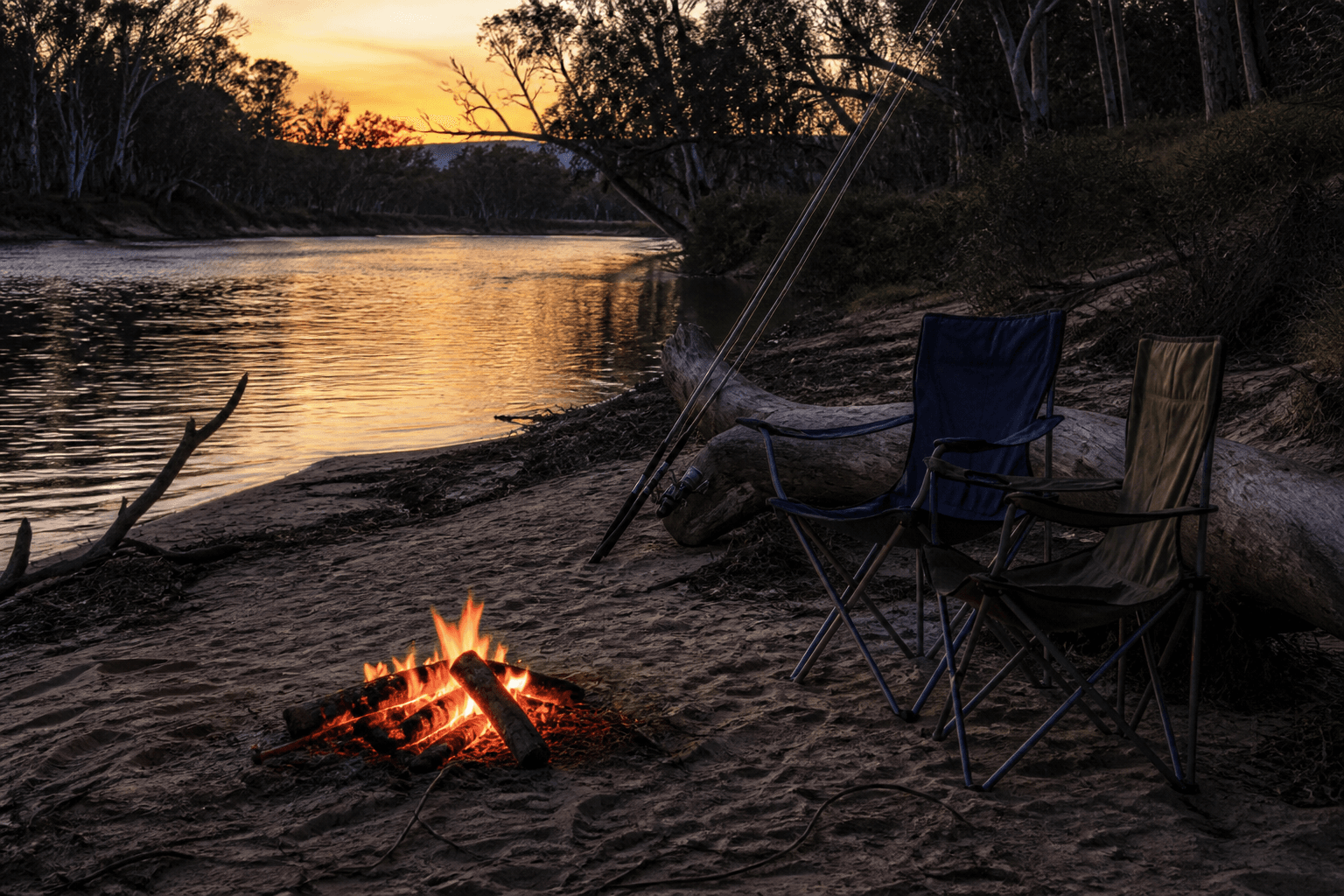 A small campfire on a riverbank at twilight